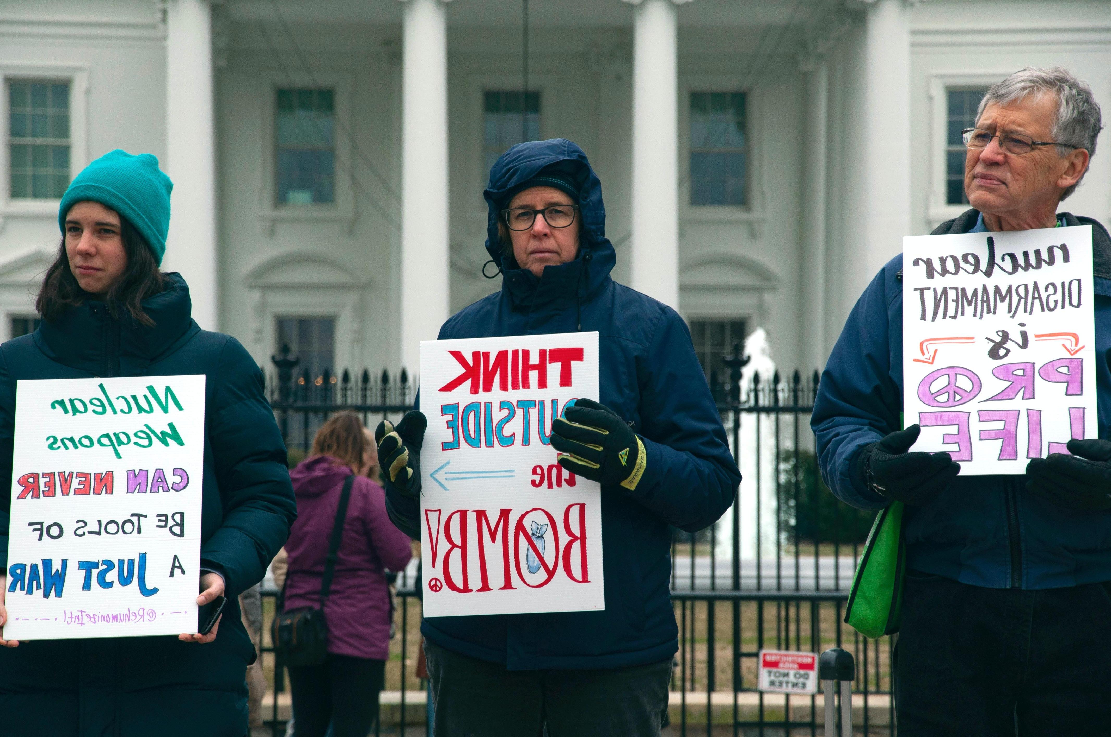 Man and two women protest nuclear weapons outside White House